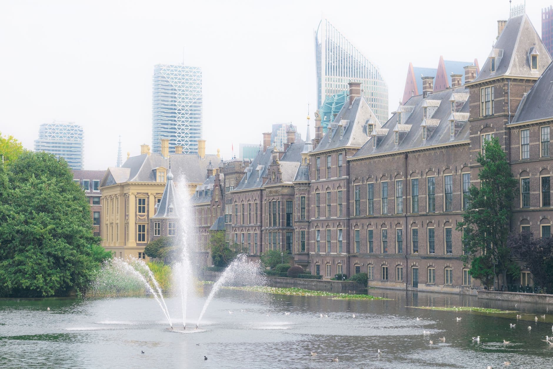 The Binnenhof in The Hague with a fountain and urban skyline backdrop.
