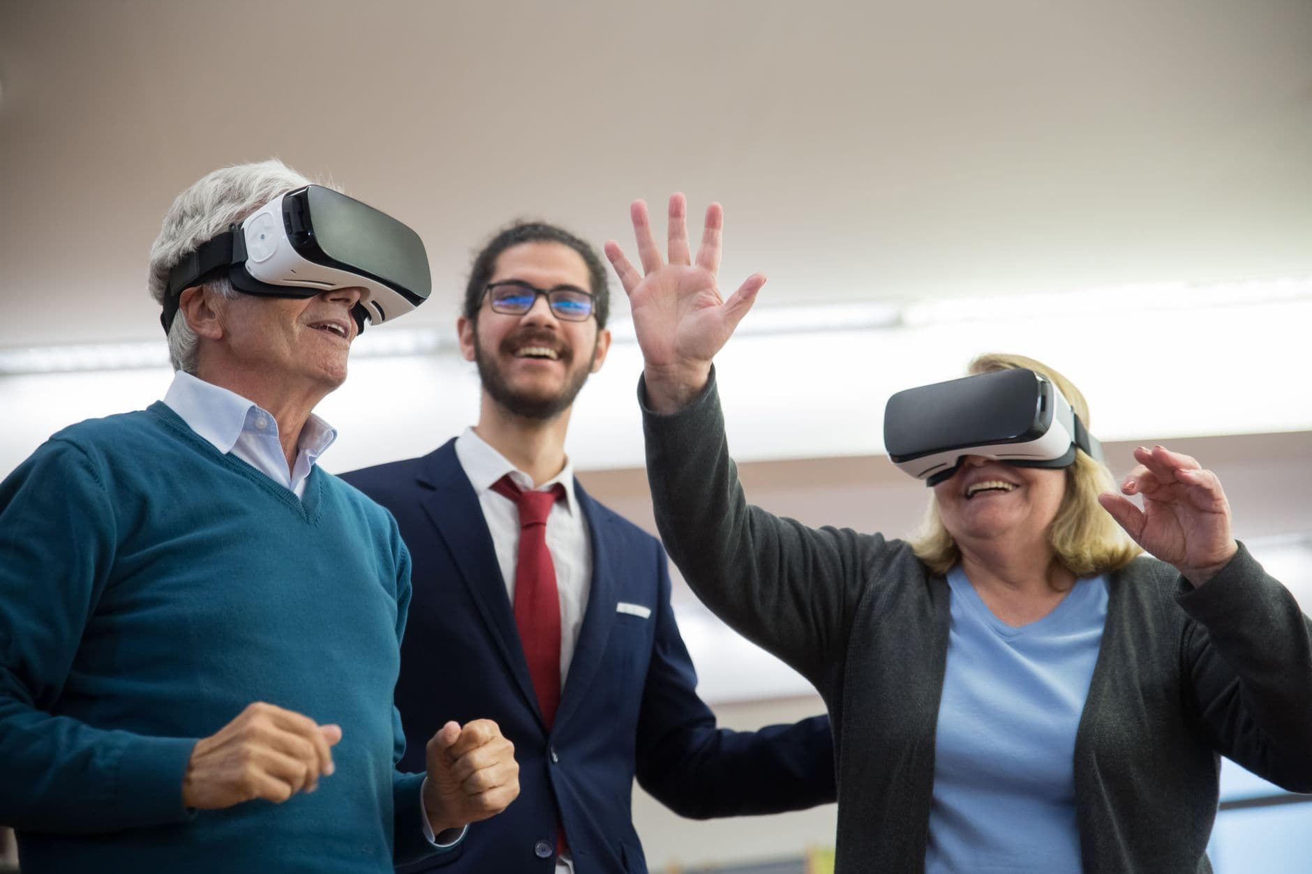 Two senior adults engaged in a fun virtual reality simulator indoors, spreading joy and technology interaction.