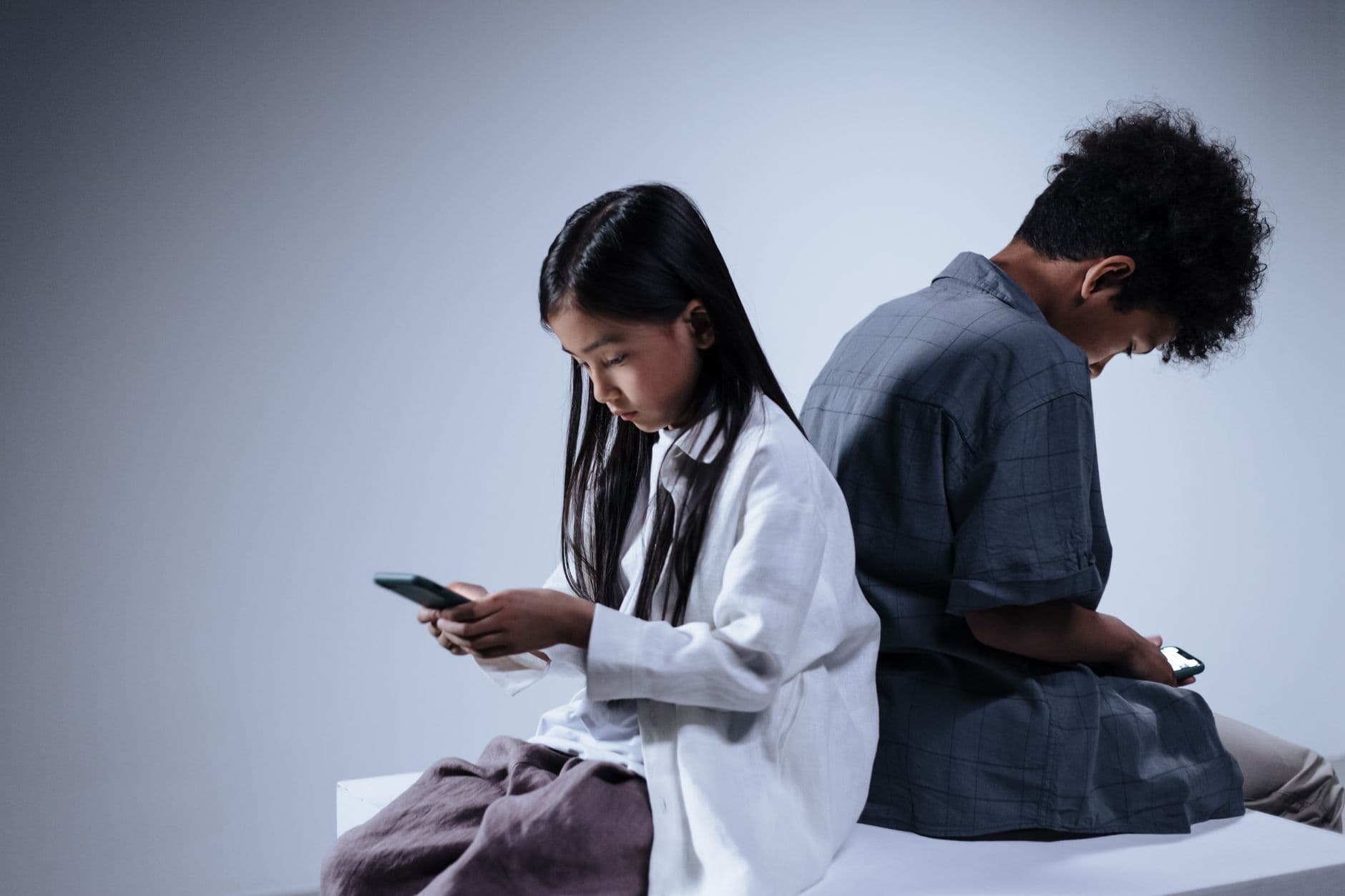 Two teenagers engrossed in their smartphones, highlighting digital connection and youth lifestyle.